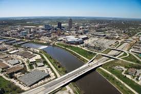 Aerial view of a cityscape featuring a river with multiple bridges and a cluster of buildings, set against a clear blue sky.
