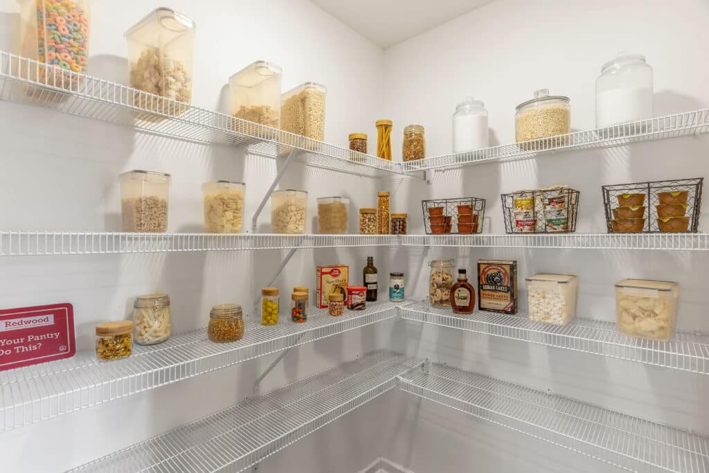 A pantry with wire shelves holding various jars, containers, and boxes filled with dry goods, snacks, and spices, all neatly organized.
