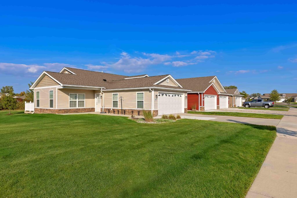 Single-story suburban houses with attached garages and well-maintained lawns on a sunny day.