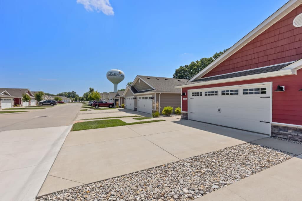 Row of suburban homes with driveways and garages on a sunny day; a water tower labeled "Bettendorf" is visible in the background.
