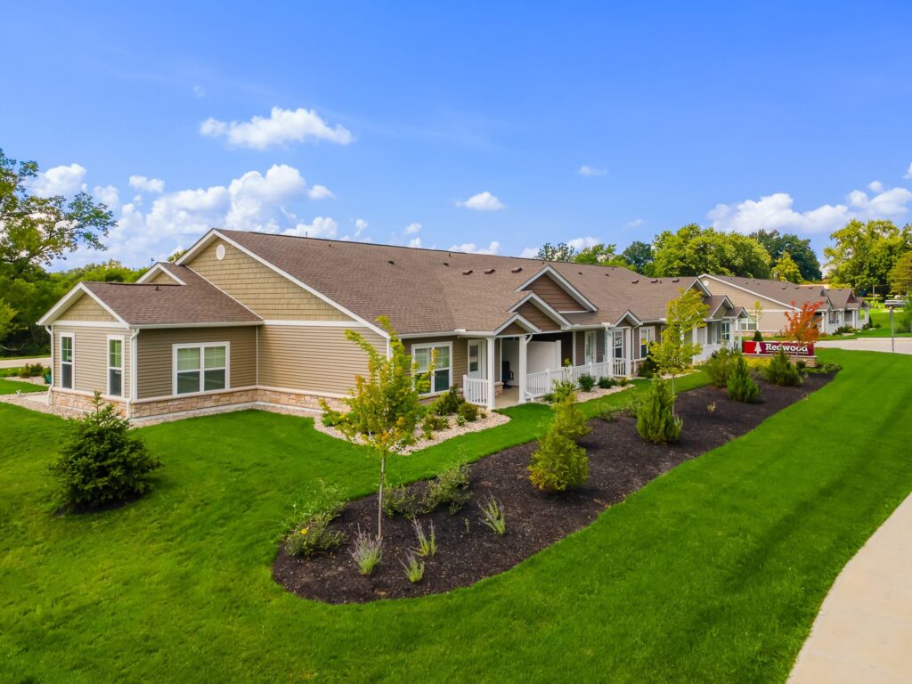 Single-story residential building with beige siding, white trim, landscaped front yard, and a clearly marked "Leasing Office" sign, set under a blue sky with scattered clouds.