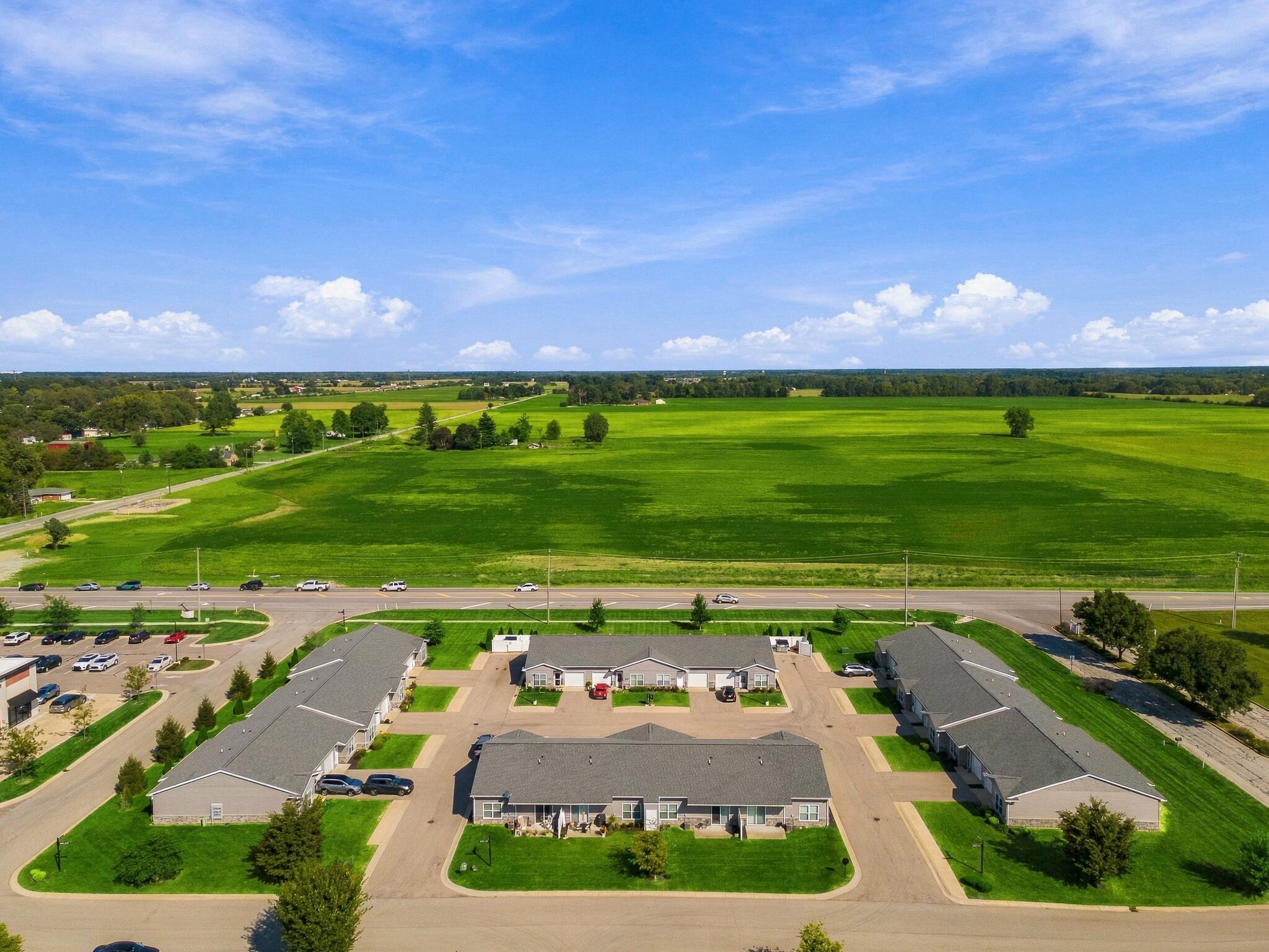 Aerial view of a residential apartment complex surrounded by large green fields.
