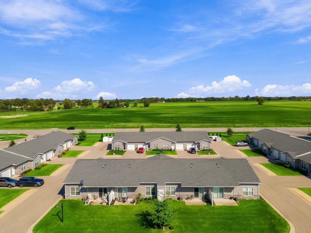 Aerial view of a residential townhouse complex surrounded by large grassy fields.